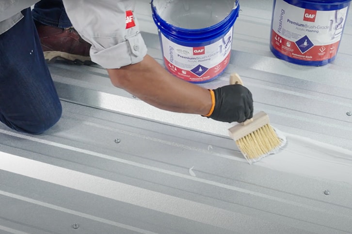 GAF certified roofing contractor applying roof coating with bulk fiber.