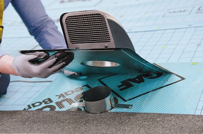 A contractor inserting the vent’s neck into a circular opening in the roof deck