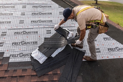Roofer separating starter strip shingles along perforated line over GAF underlayment.
