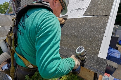 Fastening starter strip shingle with pneumatic nailer above roof eave.