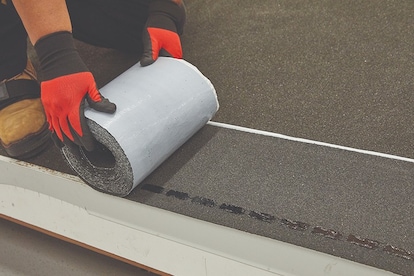 Step 1: Aligning GAF QuickStart starter roll along roof edge.