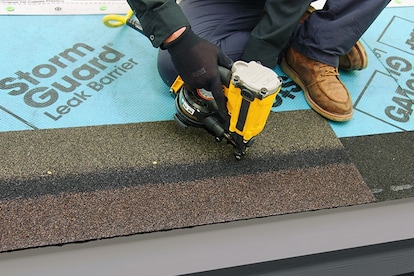 Roofer using a nail gun on a GAF starter strip over StormGuard leak barrier.