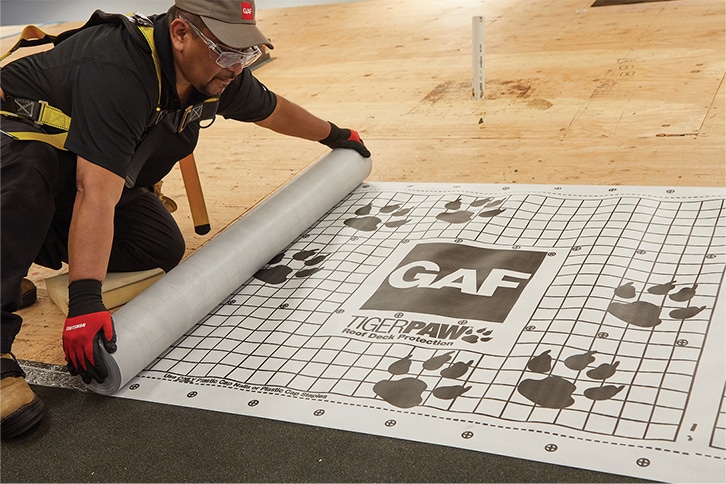 Contractors installing GAF synthetic roofing underlayment on a roof.
