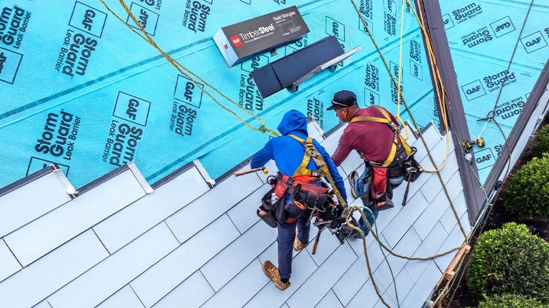 Two GAF certified contractors installing the TimberSteel Premium Metal Roofing System on a house. 